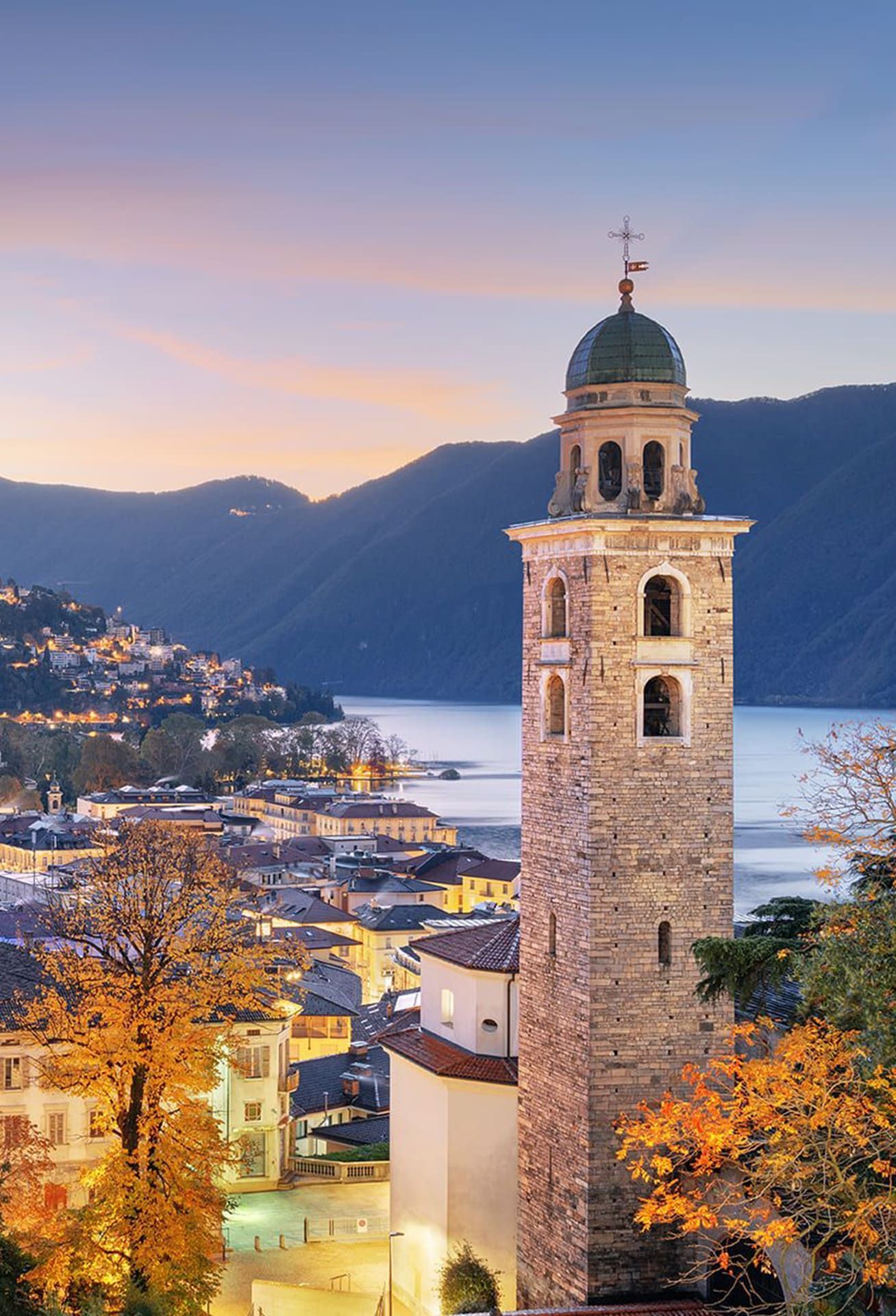 The breathtaking beauty of Lugano at sunset, with its illuminated hillside, historic architecture, and serene lake views.